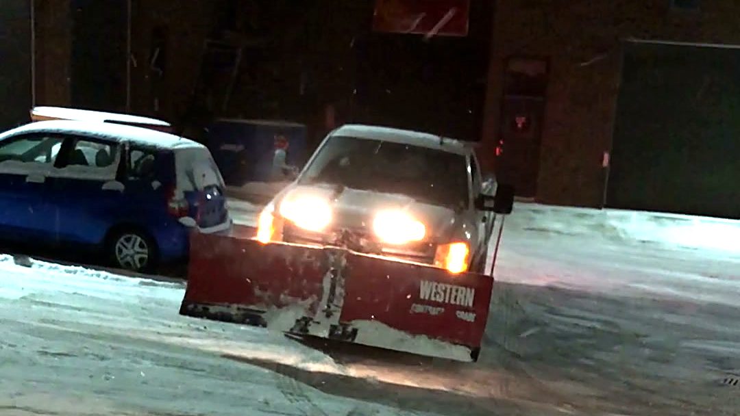 ISR Gardening snow plow truck with a red Western plow clearing snow at night