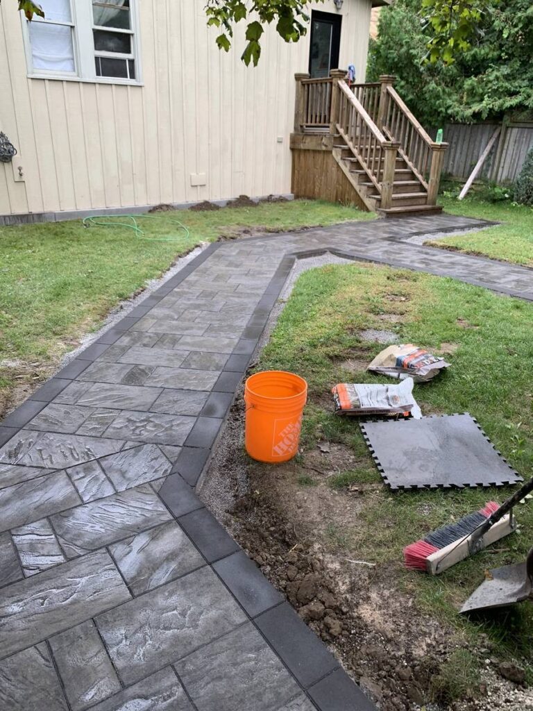 Curved interlocking walkway with border through a backyard lawn