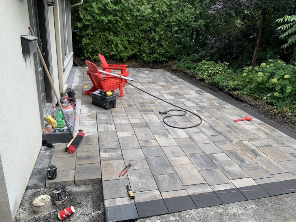 Interlocking side-yard patio being finished with a dark border